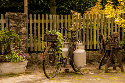 Bicycle parked on footpath by fence against trees