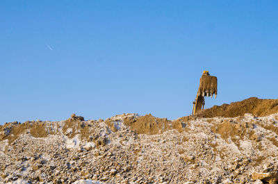 Raised excavator bucket against the blue sky. copy space.