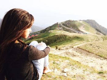 Rear view of woman standing on mountain against sky