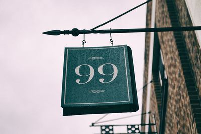 Low angle view of sign hanging against clear sky