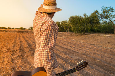 Man with acoustic guitar standing on field 