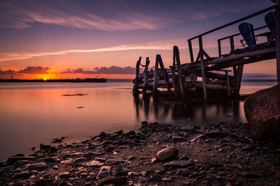 Pier over sea against sky during sunset