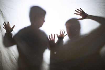 Mother and son playing with shadows behind a bed sheet