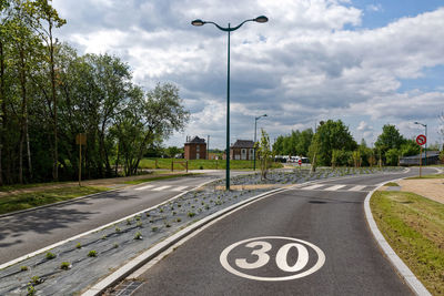 Road sign by street against sky