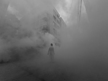 Man walking amidst smoke in city