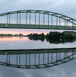 Reflection of bridge on water against sky