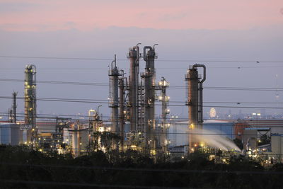 Illuminated factory against sky during sunset