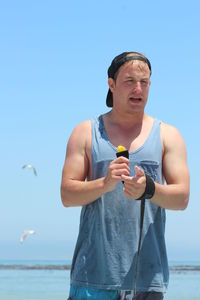 Mid adult man standing against sea against clear sky