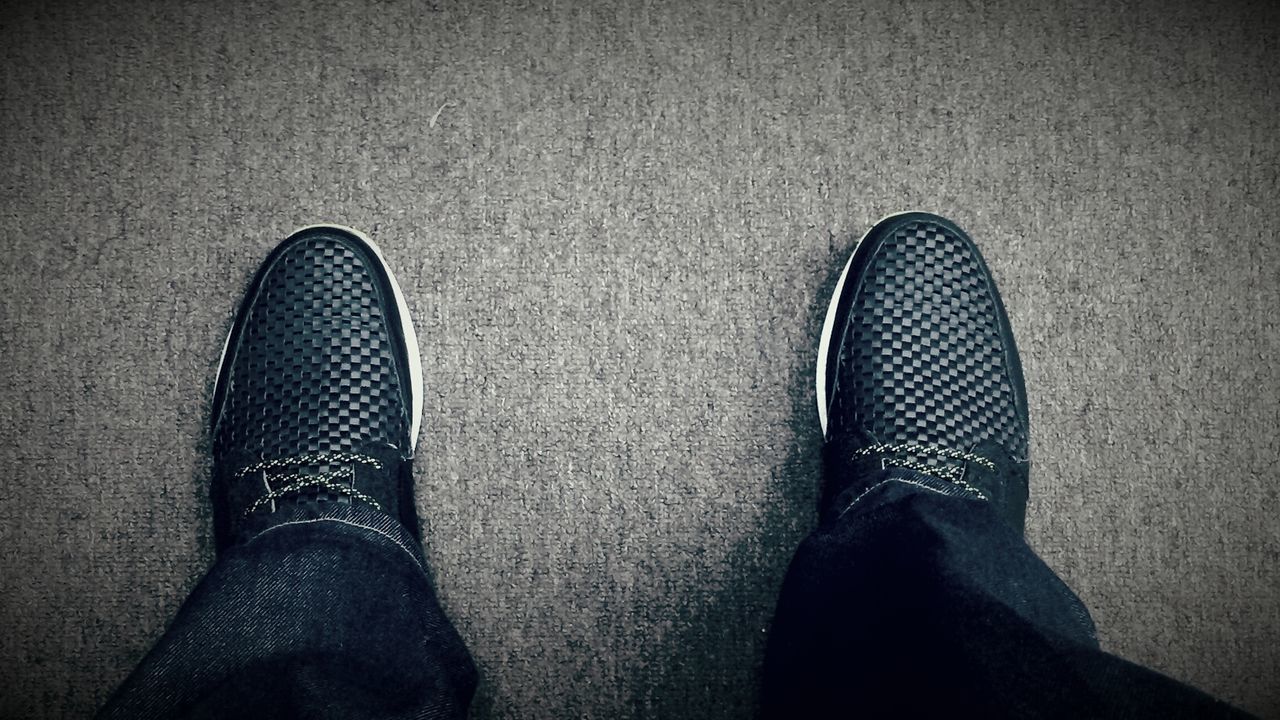 low section, person, shoe, personal perspective, footwear, high angle view, human foot, lifestyles, unrecognizable person, standing, men, leisure activity, directly above, part of, black color, jeans, pattern