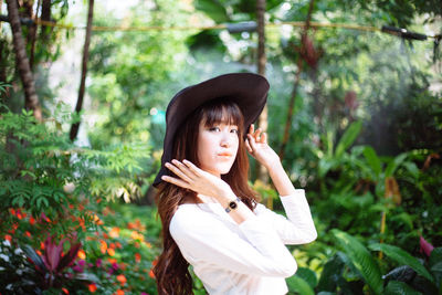 Portrait of young woman standing against plants