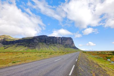 Road passing through landscape against cloudy sky