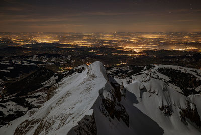 High angle view of snow covered mountain against sky at night