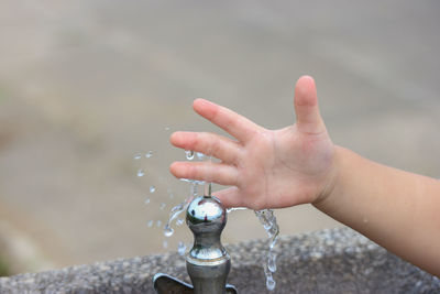 Cropped hand of child by drinking fountain