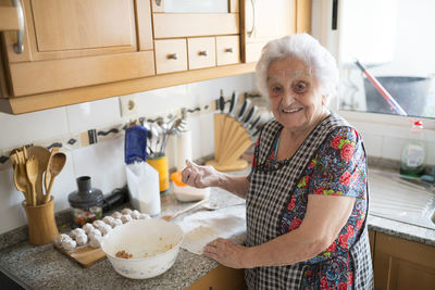 Portrait of smiling senior woman preparing meatballs in the kitchen