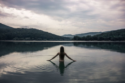 Rear view of man standing on lake against sky