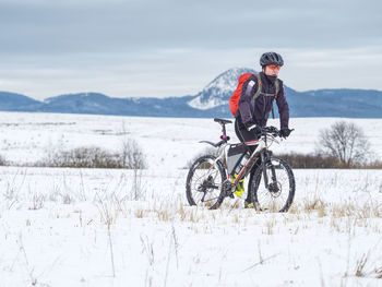 Man riding bicycle on field during winter