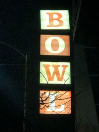 Low angle view of illuminated sign on wall at night