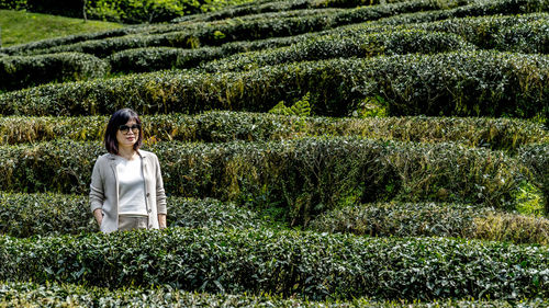 Portrait of woman standing against plants