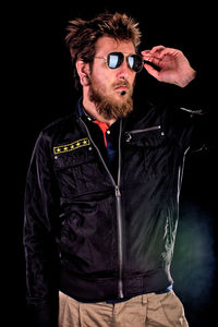 Portrait of man standing against black background