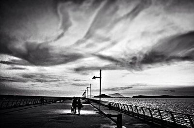 Pier on sea against cloudy sky