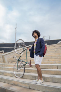 Stylish man with bicycle on stairs in the city