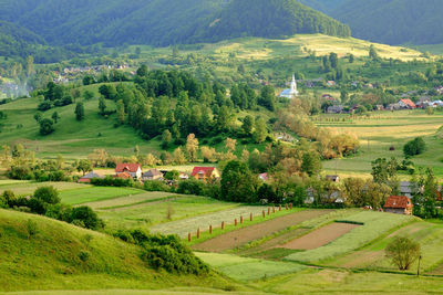 Scenic view of green landscape and houses against mountain