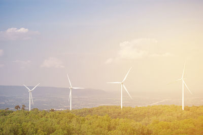 Wind turbines on field against sky