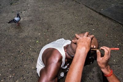 Cropped hands of barber shaving man head outdoors