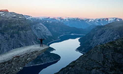 Rear view of person on cliff against valley during sunset