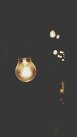 Low angle view of lit light bulb at night