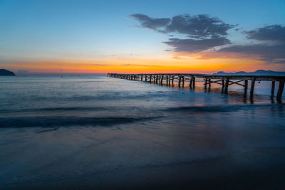 Pier over sea against sky during sunset