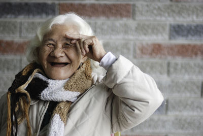 Close-up portrait of happy senior woman standing against wall