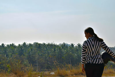 Young man standing on field against sky