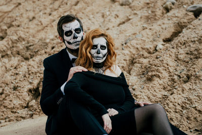 A couple in love is sitting hugging against the backdrop of mountains celebrating halloween in costu