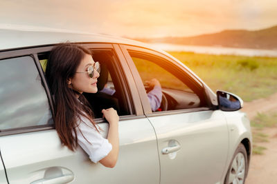 Young woman looking down while sitting in car