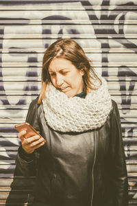 Young woman using mobile phone while standing outdoors
