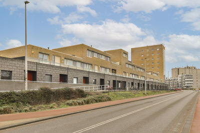 Empty road by buildings against sky