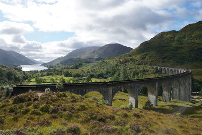 Arch bridge over mountains against sky