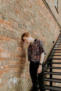 Full length of man standing against brick wall