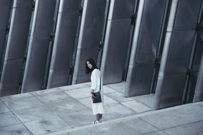 Portrait of young woman standing by modern building