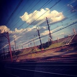 Low angle view of electricity pylon against blue sky