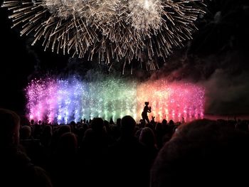 People looking at firework display at night