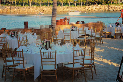Empty chairs and tables in restaurant at beach