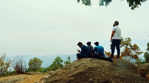 Rear view of people sitting on rock