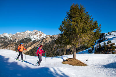 People on snowcapped mountain against clear blue sky