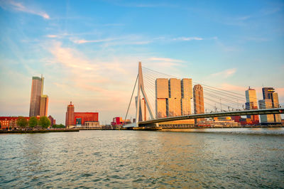 Suspension bridge over river with city in background