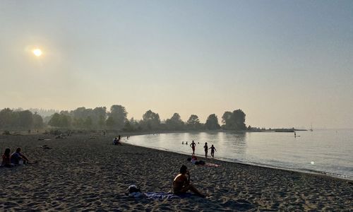 People on beach against clear sky