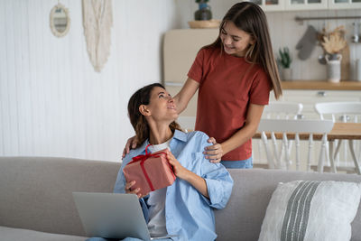 Side view of woman using digital tablet while sitting on sofa at home