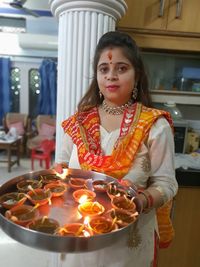 Portrait of woman holding diyas in plate at home