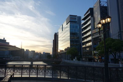 City buildings by canal against sky